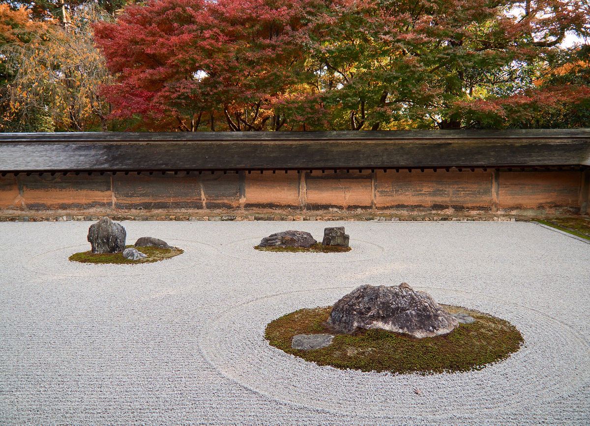 Der Steingarten des Ryōan-ji in Kyoto mit geharktem Kies, Steingruppen und Herbstlaub
